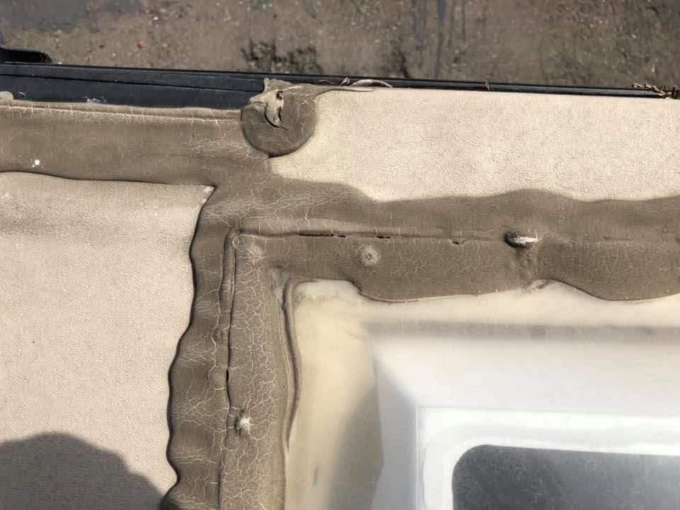 Close-up of a cracked beige car door seal and weathered trim around a window edge.