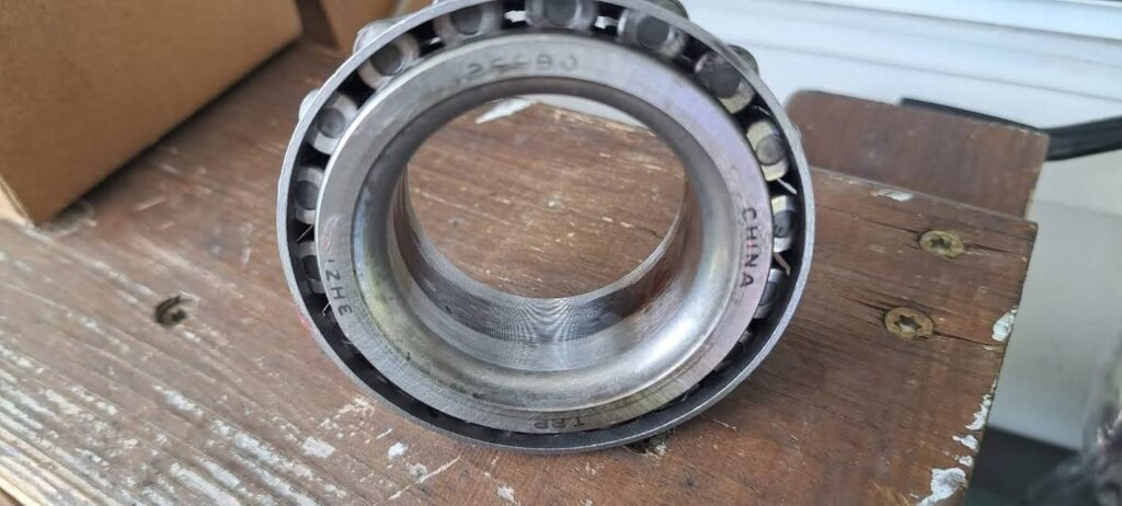 Burnt Wheel bearing - California RV Specialists Close-up of a metal ball bearing on a wooden workbench, showing the inner threaded ring and the CHINA marking on the outer race.