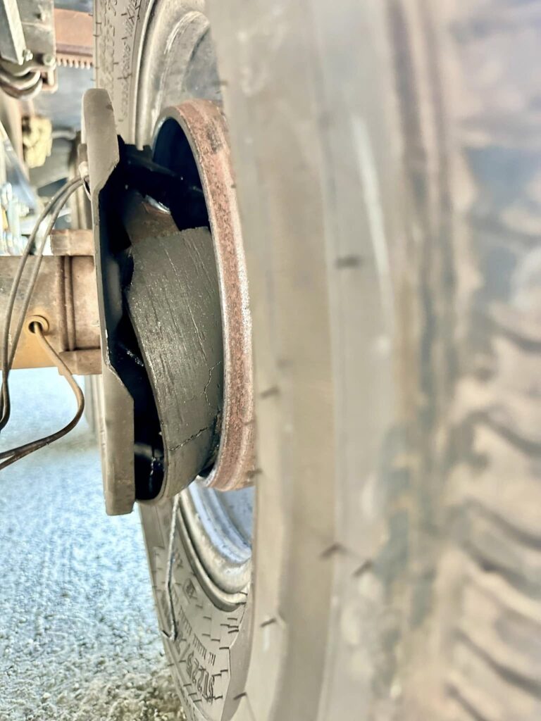 Hubs coming off - California RV Specialists Close-up of a car wheel showing a cracked tire sidewall and a rusted rim; the brake rotor and suspension components are faintly visible near the wheel.