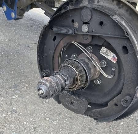 Wheel bearing damage - California RV Specialists Trailer drum brake assembly with exposed hub and axle shaft, showing brake backing plate, springs, and wiring