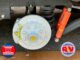 RV trailer undercarriage showing exposed brake rotor, hub, coil spring, and orange shock absorbers; logos read 'Your RV Specialists' and 'California RV Specialists'