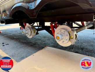 RV undergoing brake maintenance with wheels removed, showing exposed brake rotors and wheel hubs undercarriage on stands
