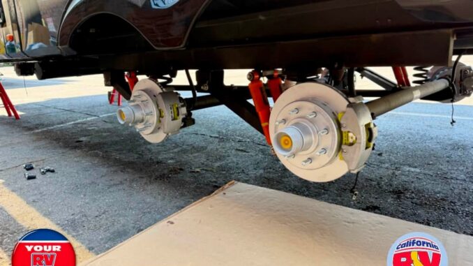 RV undergoing brake maintenance with wheels removed, showing exposed brake rotors and wheel hubs undercarriage on stands
